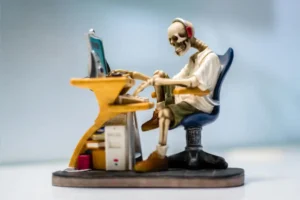 A skeleton sat patiently waiting at an apparently slow computer.